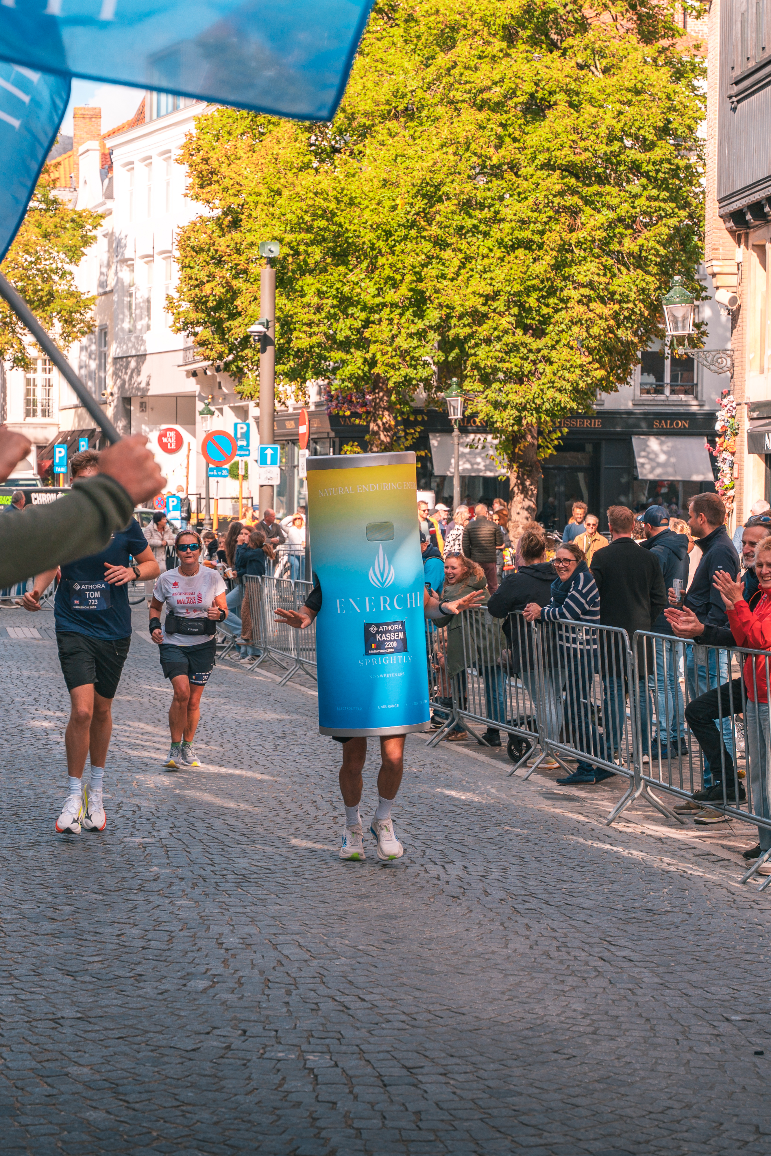Founder Kassem running the Bruges marathon in an EnerChi can costume while spectators cheer